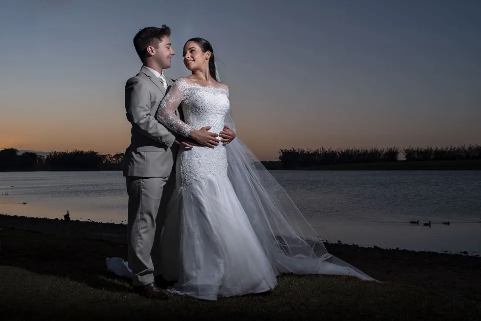 Noivos abraçados diante do lago no crepúsculo